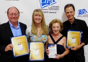 Four people holding up awards in front of a white wall.