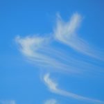 A blue sky with some clouds in the shape of an animal
